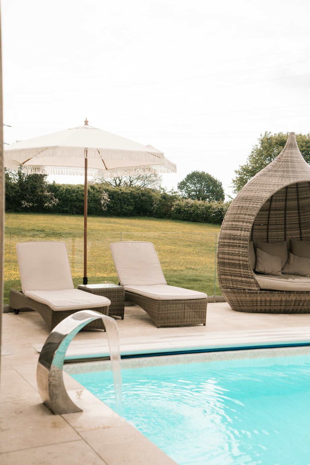 Peaceful poolside loungers, a woven daybed and flowing water at the sanctuary